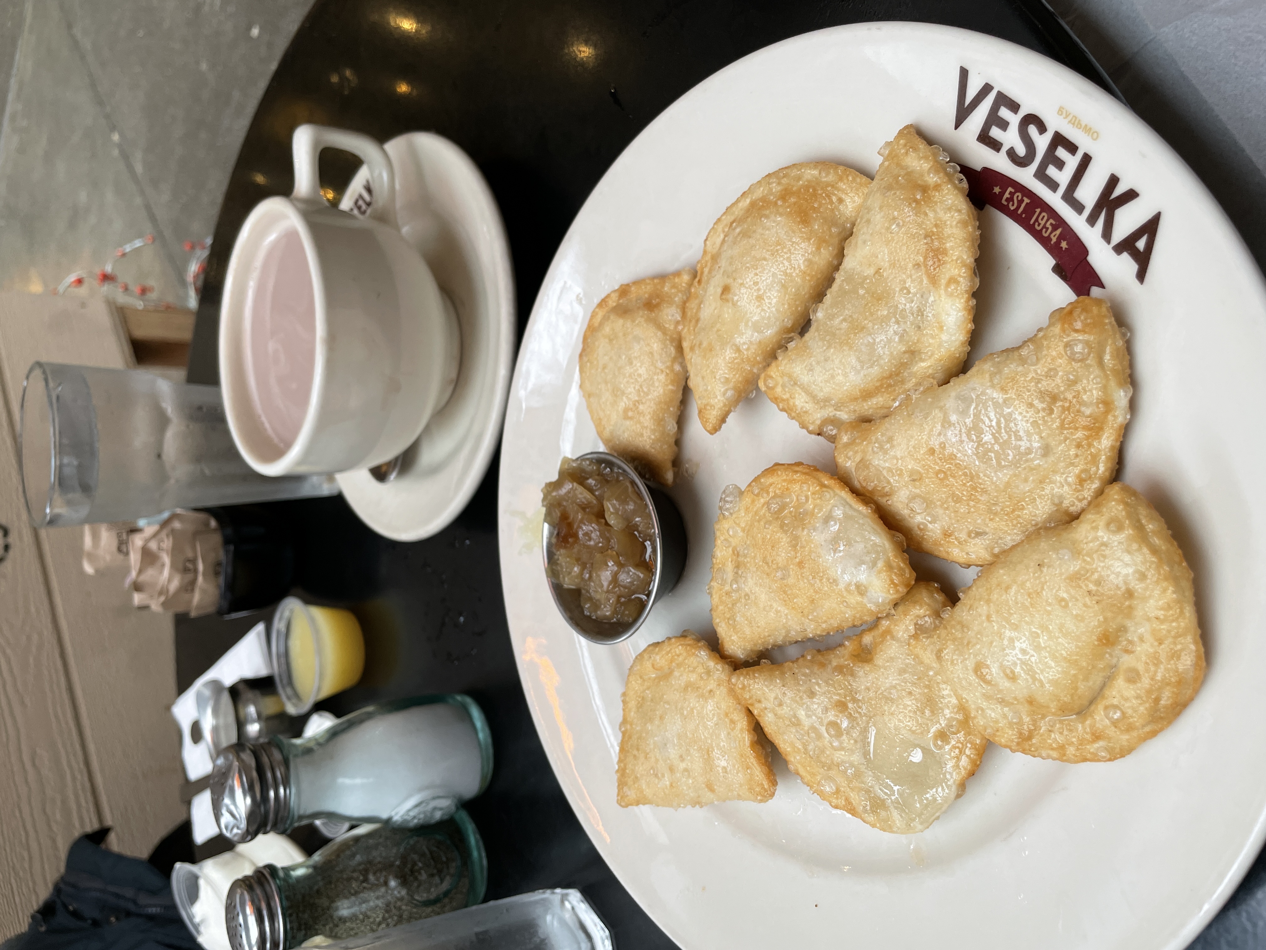 plate of pierogi and a glass of prosecco, with 2 other's meals visible to the side.