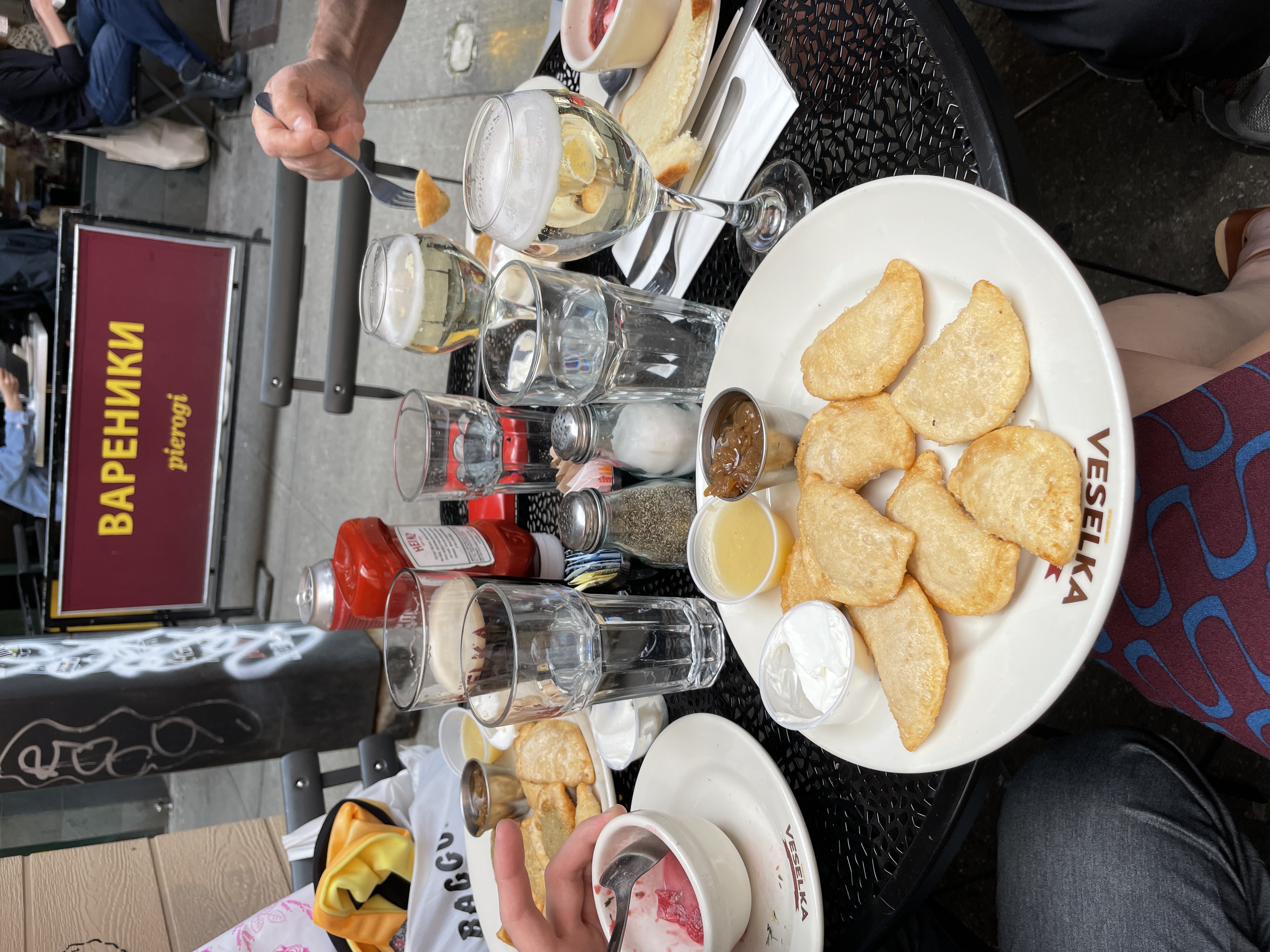 plate of pierogi and a glass of prosecco, with 2 other's meals visible to the side.